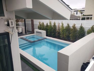 Modern pool and spa with light coping, a spa spillway, and white plaster