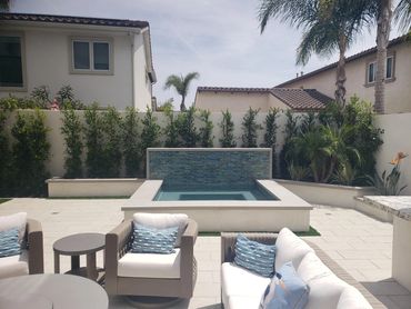 Raised spa with tiled spillway wall beside a patio seating area