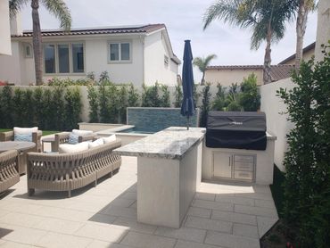 Backyard outdoor kitchen and patio seating next to a raised spa with tiled wall