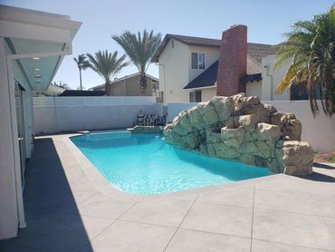 Pool with a rock waterfall feature and wide concrete deck