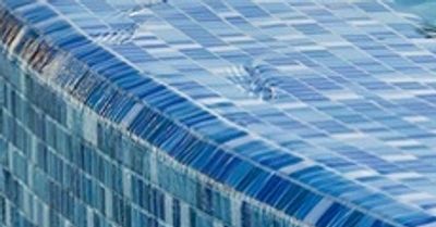 Close-up of a spa edge finished in blue glass mosaic tile