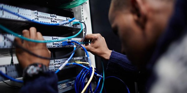 Technician connecting cables in a network equipment rack