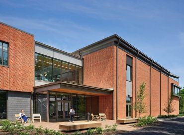 Modern brick building with large windows and benches outside.