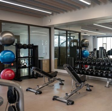 Modern gym with benches, weights, and exercise balls.