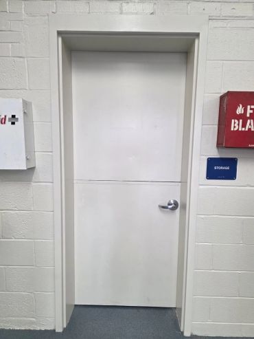 White storage room door with emergency boxes on the wall.