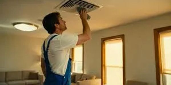 A man cleaning an air vent indoors.