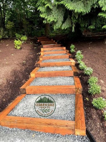 Wooden framed gravel steps surrounded by greenery in a garden.