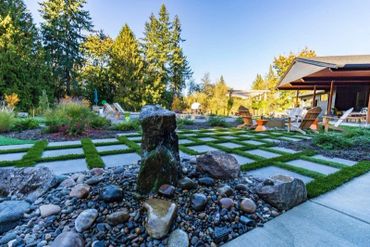 Modern backyard with stone water feature and checkerboard lawn design.