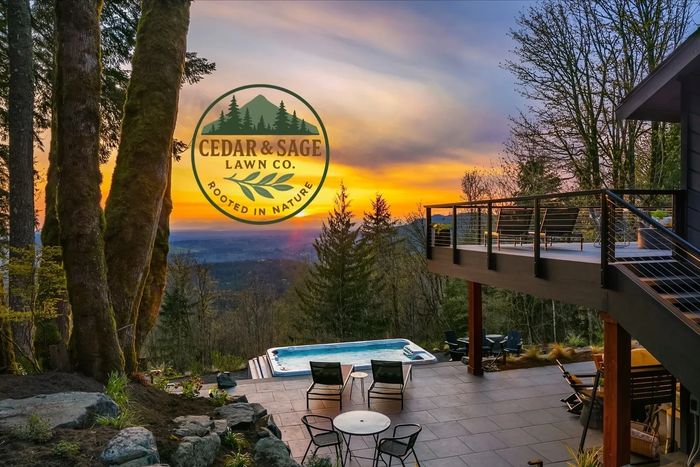 Scenic backyard with hot tub and sunset view, showcasing Cedar & Sage Lawn Co. logo.
