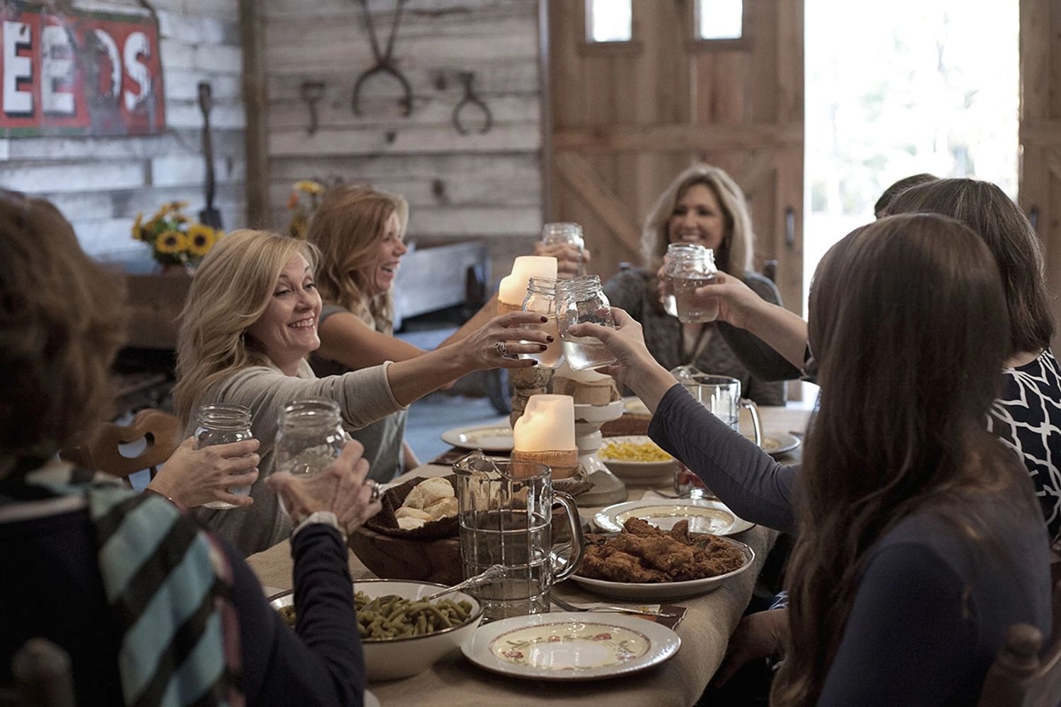 Women enjoying a cheerful gathering and toasting with drinks around a dining table.