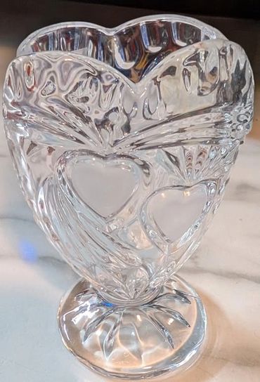 Clear glass vase with heart-shaped patterns on a pedestal base.