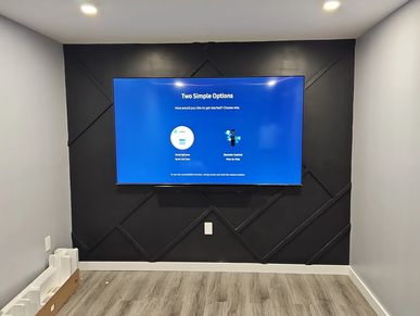 Modern TV mounted on a black accent wall in a minimalist room.