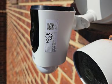 Two white security cameras mounted on a brick wall.