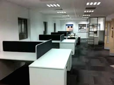 Empty modern office space with white desks and black partitions.