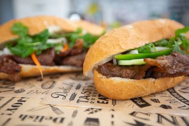 Close-up of two Vietnamese banh mi sandwiches with grilled meat and fresh vegetables.