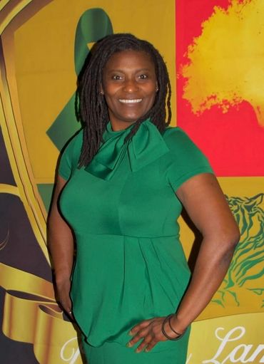 Woman in green dress smiling confidently against colorful backdrop.