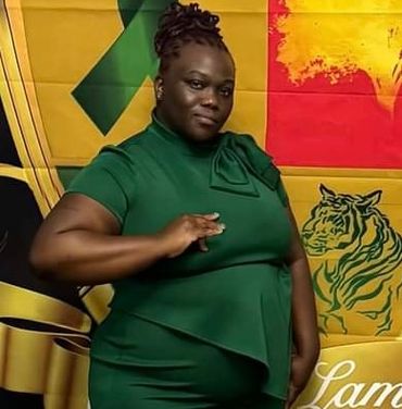Woman in green dress posing confidently before a colorful backdrop.