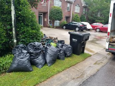 Black trash bags and bulk junk staged by the curb for Haul Squad pickup