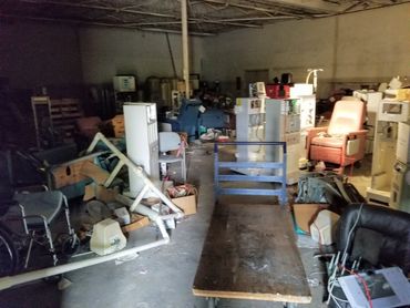Pallets of junk and machinery cluttering a facility before cleanout