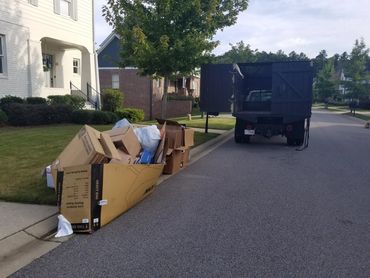 Before photo with junk and boxes ready for hauling service outside on the curb
