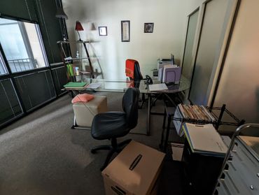 Disorganized office with chairs, boxes, and electronics before junk removal