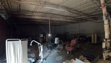 Inside of abandoned facility filled with junk, furniture, and large equipment