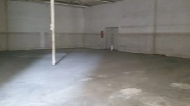 Warehouse showroom with chairs, tables, and clutter being emptied