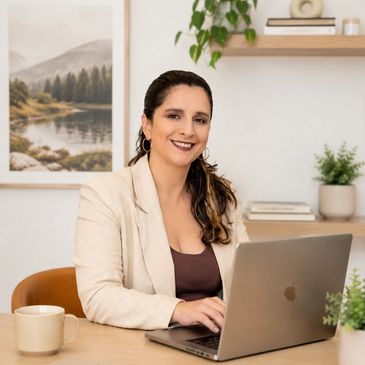 Smiling woman working on a laptop in a cozy, modern office with plants and artwork.