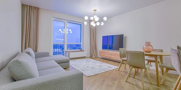 Modern living room with gray sofa, wooden floor, and round dining table.