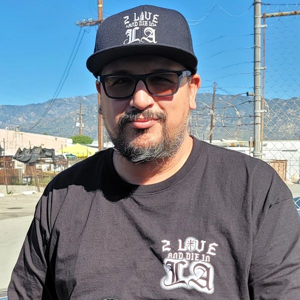 Man outside car wearing a black hat and shirt.