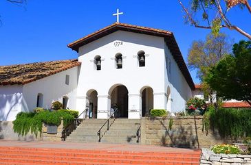 A white mission-style church with three arches and a cross on top.