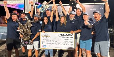 Group celebrating with a large check and trophy at a fishing tournament.