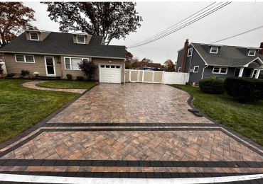 Newly paved driveway with intricate brick pattern and clean landscaping.