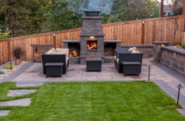 Cozy outdoor patio with a stone fireplace and seating area.