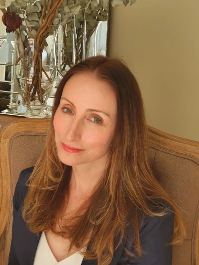 Woman with long brown hair smiling gently.