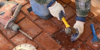 Worker chiseling bricks on a construction site with tools.