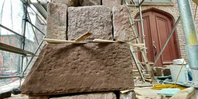Close-up of a stone pillar under restoration with scaffolding around it.