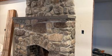 Rustic stone fireplace in a wooden-beamed room.