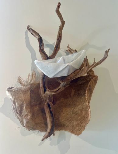Paper boat on driftwood and textured surface.