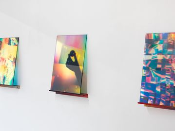 Three colorful abstract artworks displayed on a white gallery wall.