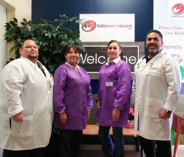 Four healthcare professionals posing in front of a lab services welcome sign.