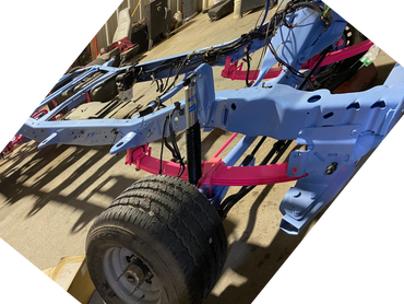 Partially assembled vehicle frame with blue chassis and pink leaf springs in a workshop.