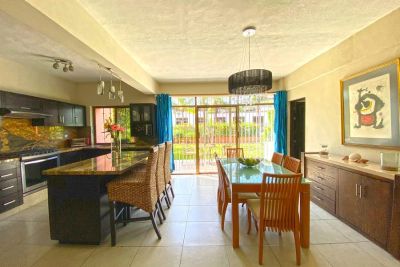 Bright modern kitchen and dining area with large windows and wooden furniture.