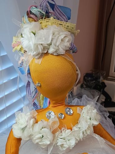 Handmade orange fabric doll dressed in white tulle and adorned with flowers and jewels.