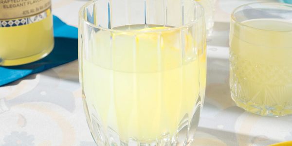 Two glasses of refreshing lemonade on a table with a lemon wedge.