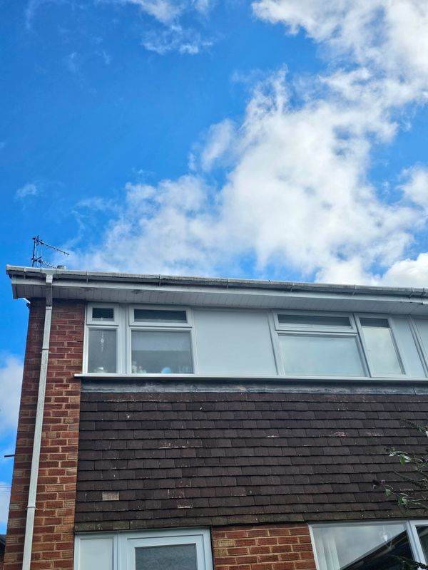 Exterior view of a two-story house under a partly cloudy blue sky.
