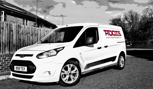 White Ford van with Roots Transport branding parked on street.