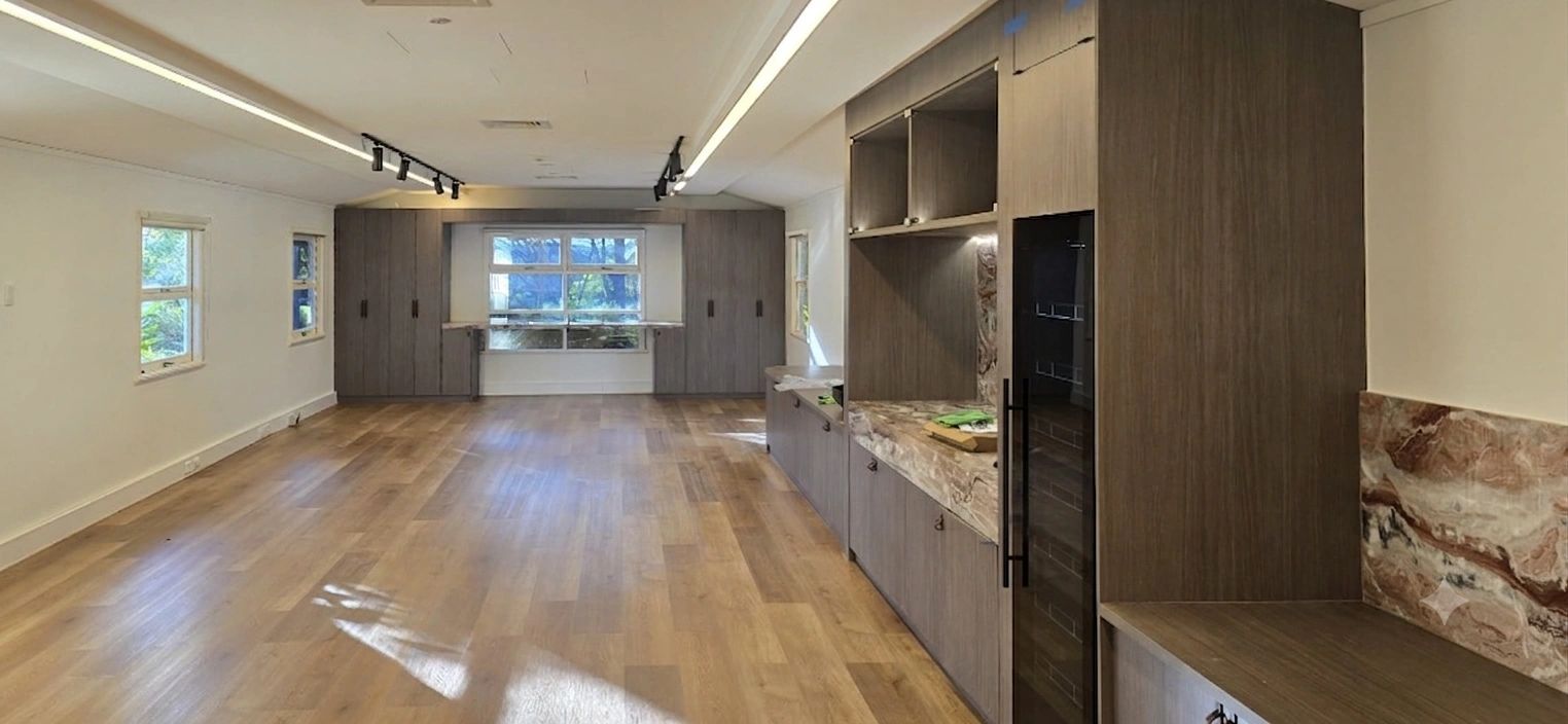 Spacious room with wooden flooring and cabinetry.