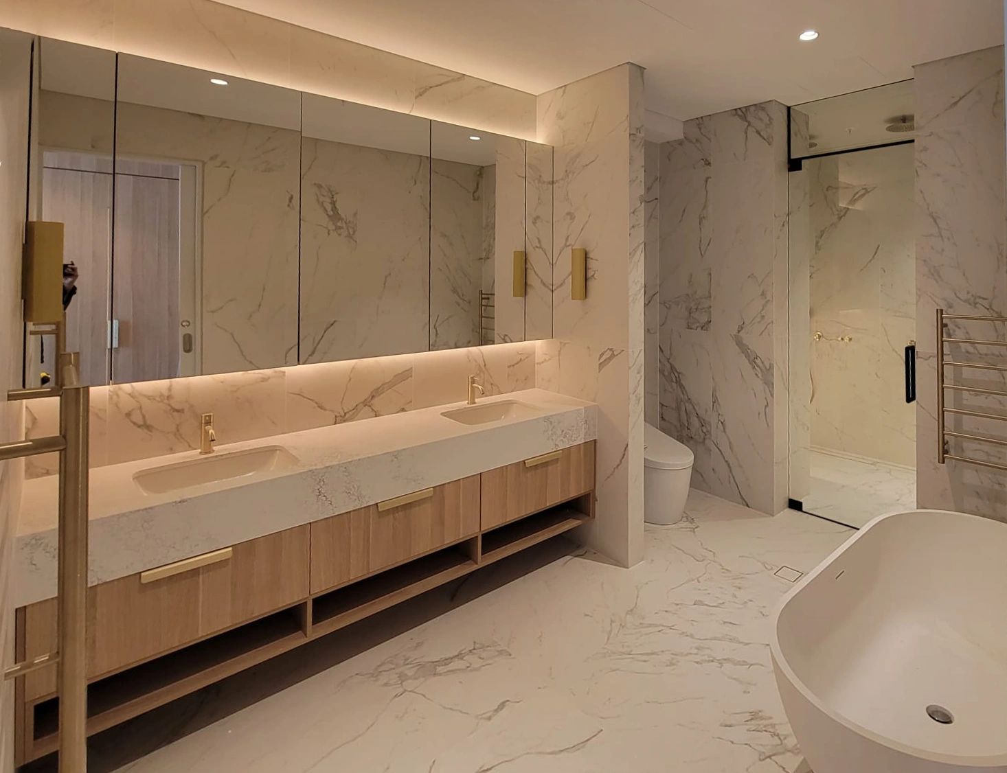 Modern bathroom with marble and wood finishes.