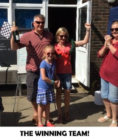 Family celebrating outdoors with a trophy and a champagne bottle.